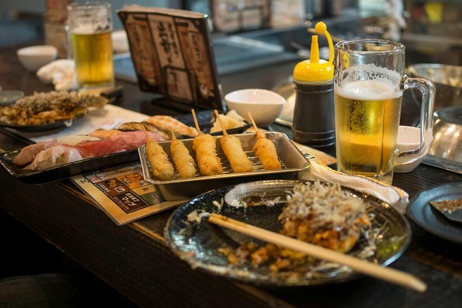 A plate of kushikatsu skewers and a glass of beer on a bar counter