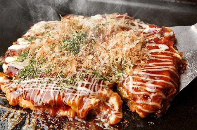 An okonomiyaki finished with sauce and bonito flakes