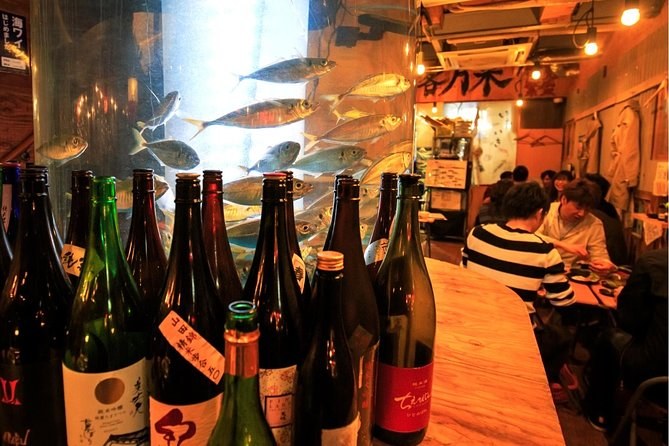 Sake bottles lined along the counter of a small izakaya