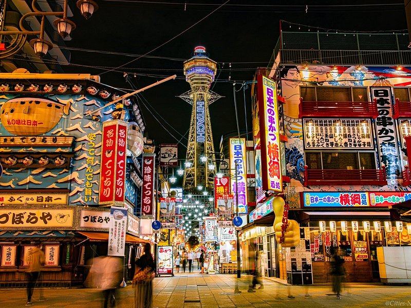 Shinsekai's stacked signboards and Tsutenkaku lit after dark