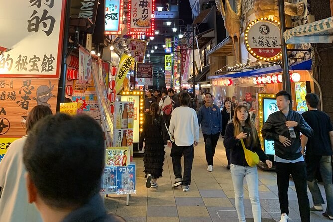 Shinsekai's signboards above an evening crowd