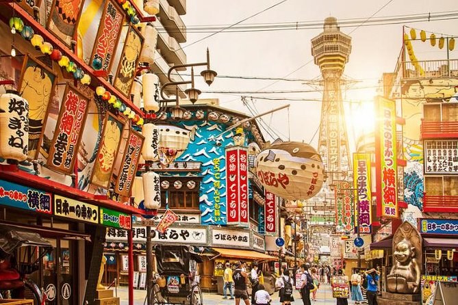 Tsutenkaku rising over the Shinsekai signboards at sunset