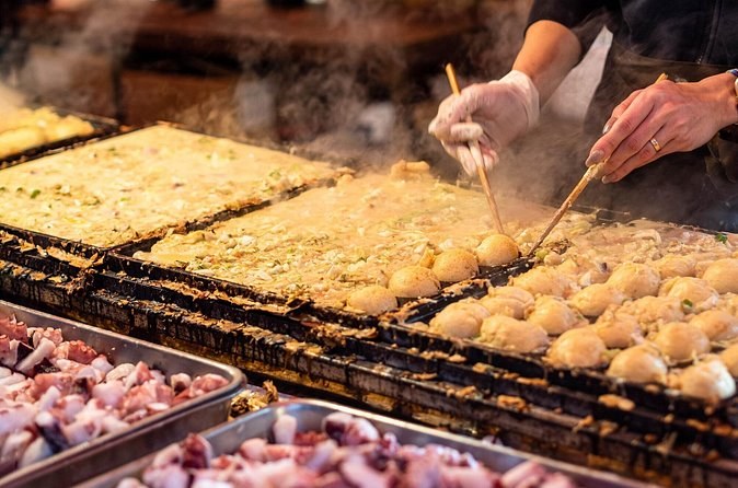 Takoyaki being turned in a cast-iron hot plate